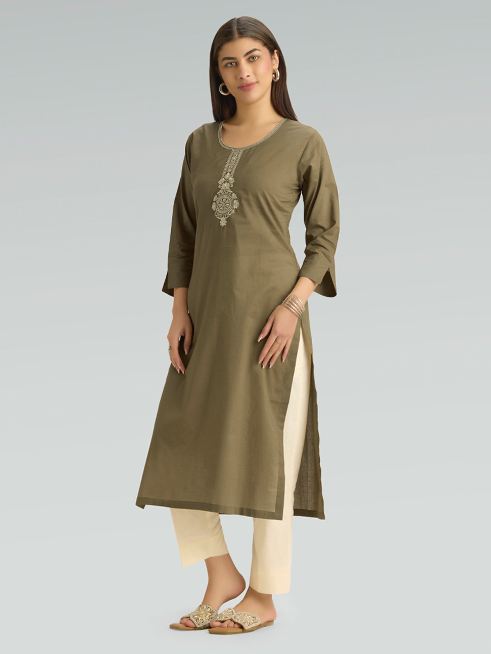 Woman wearing an olive green kurta with beige pants on a gray background