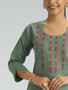 Green embroidered dress worn by a person on a plain background