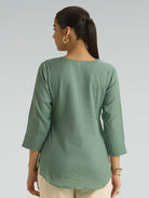 Woman wearing a green top with a plain background