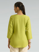 Woman wearing a green top with a plain background