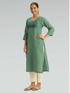 Woman wearing a green kurta with embroidery on a gray background