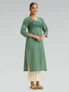 Woman wearing a green kurta with embroidery on a gray background