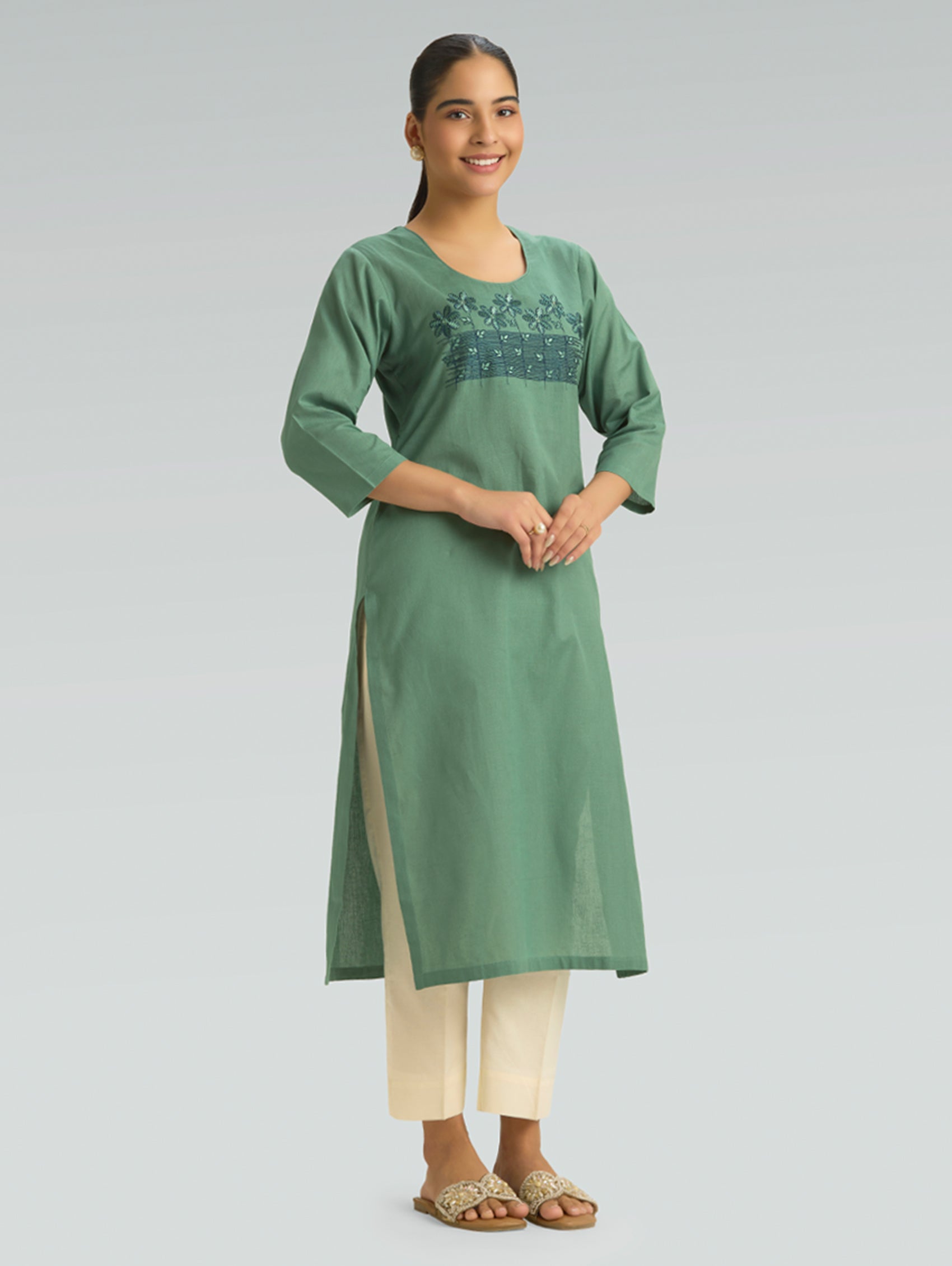 Woman wearing a green kurta with embroidery on a gray background