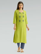 Woman wearing a green kurta with embroidery on a gray background