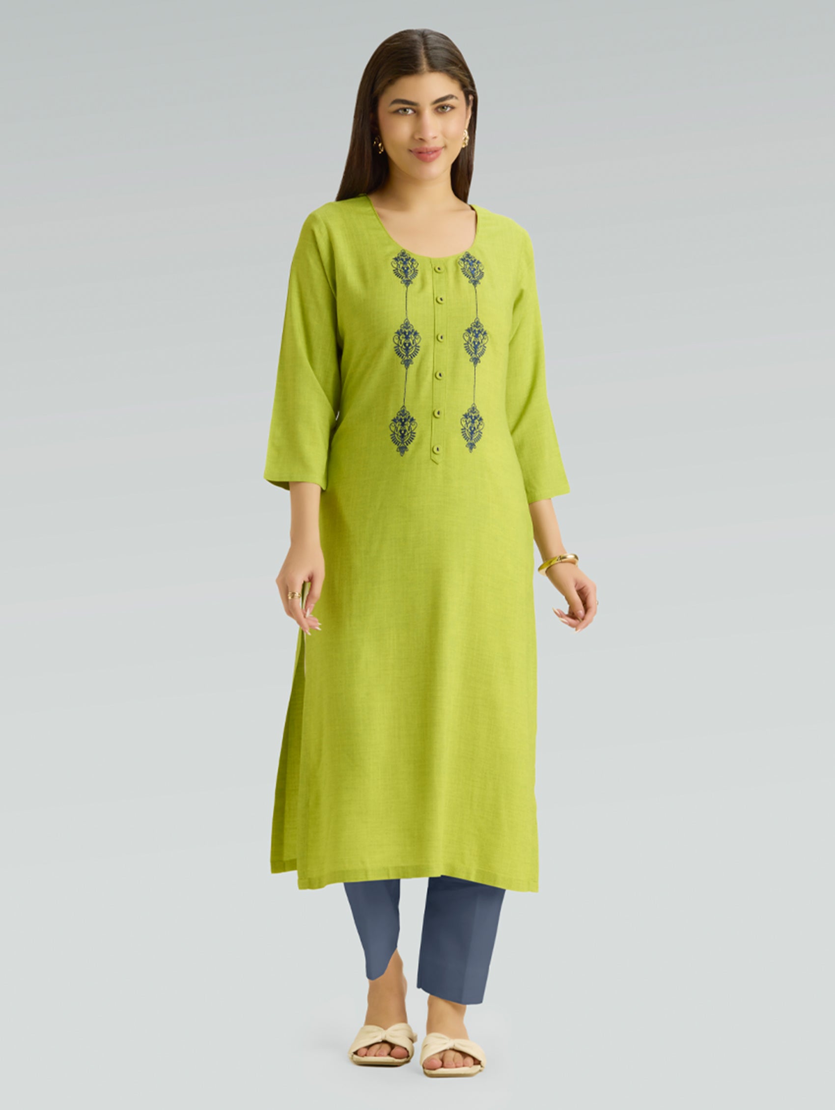 Woman wearing a green kurta with embroidery on a gray background