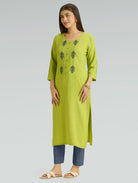 Woman wearing a green kurta with embroidery on a gray background