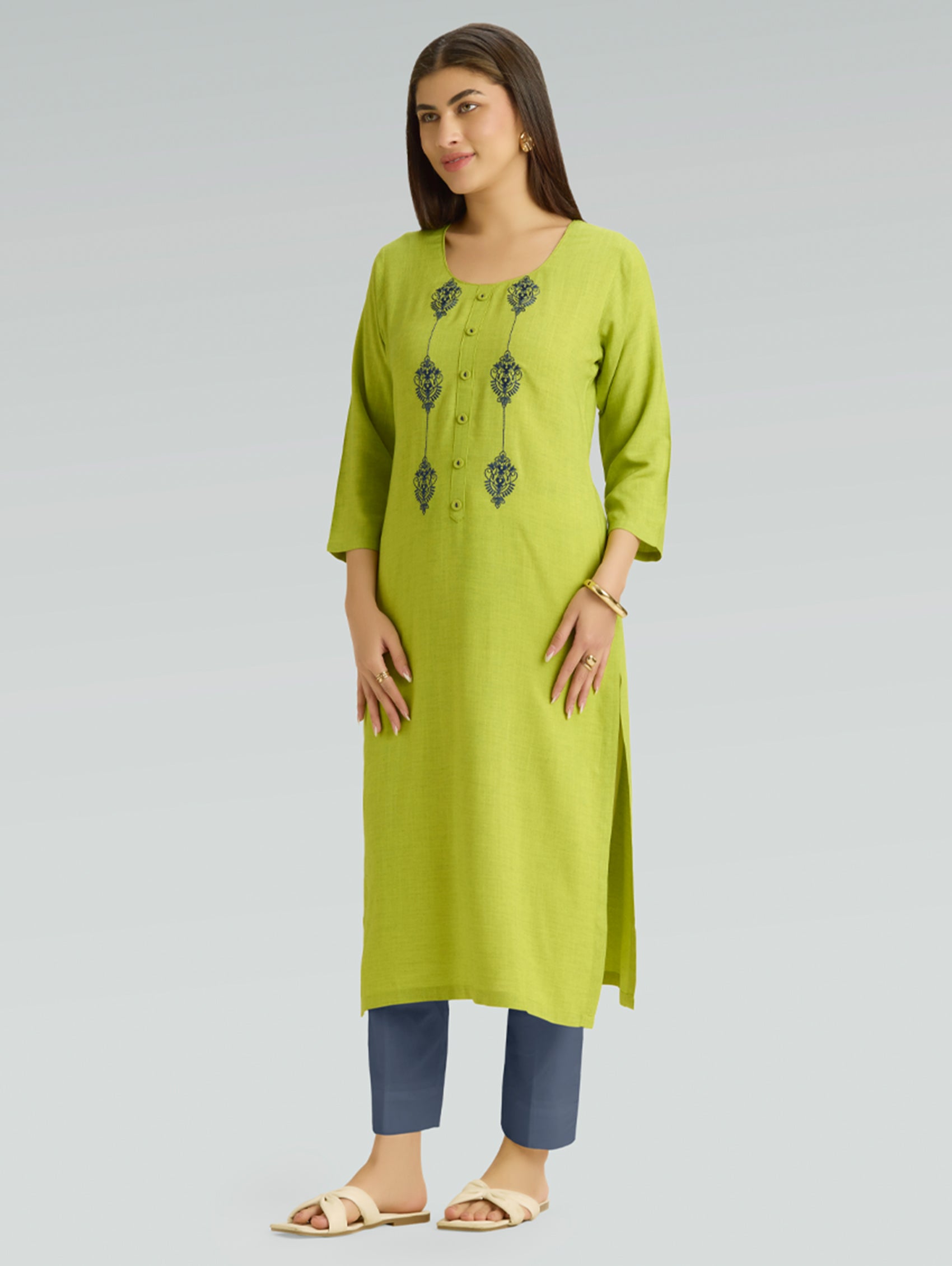 Woman wearing a green kurta with embroidery on a gray background