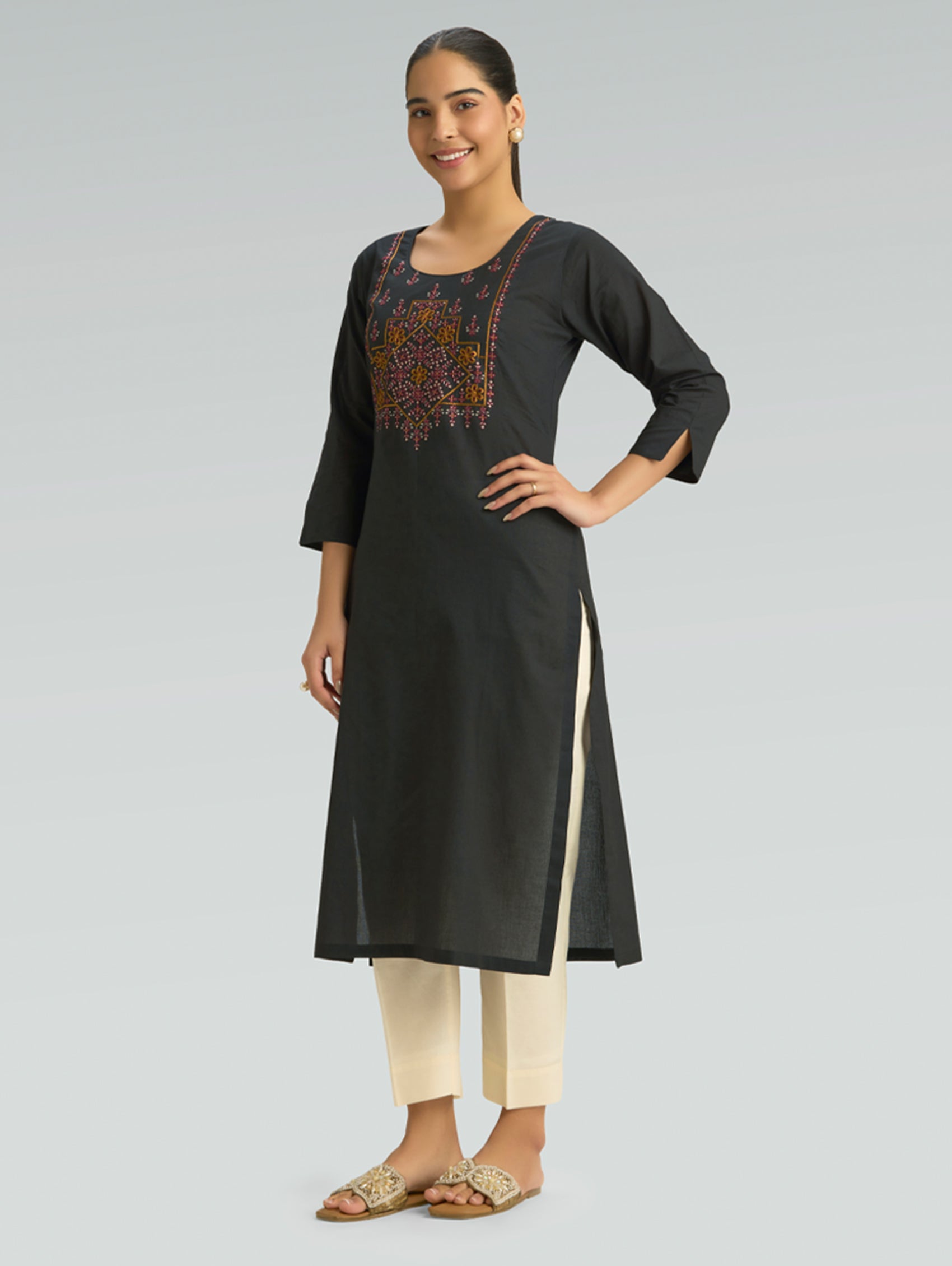 Woman wearing a black kurta with embroidery on a gray background