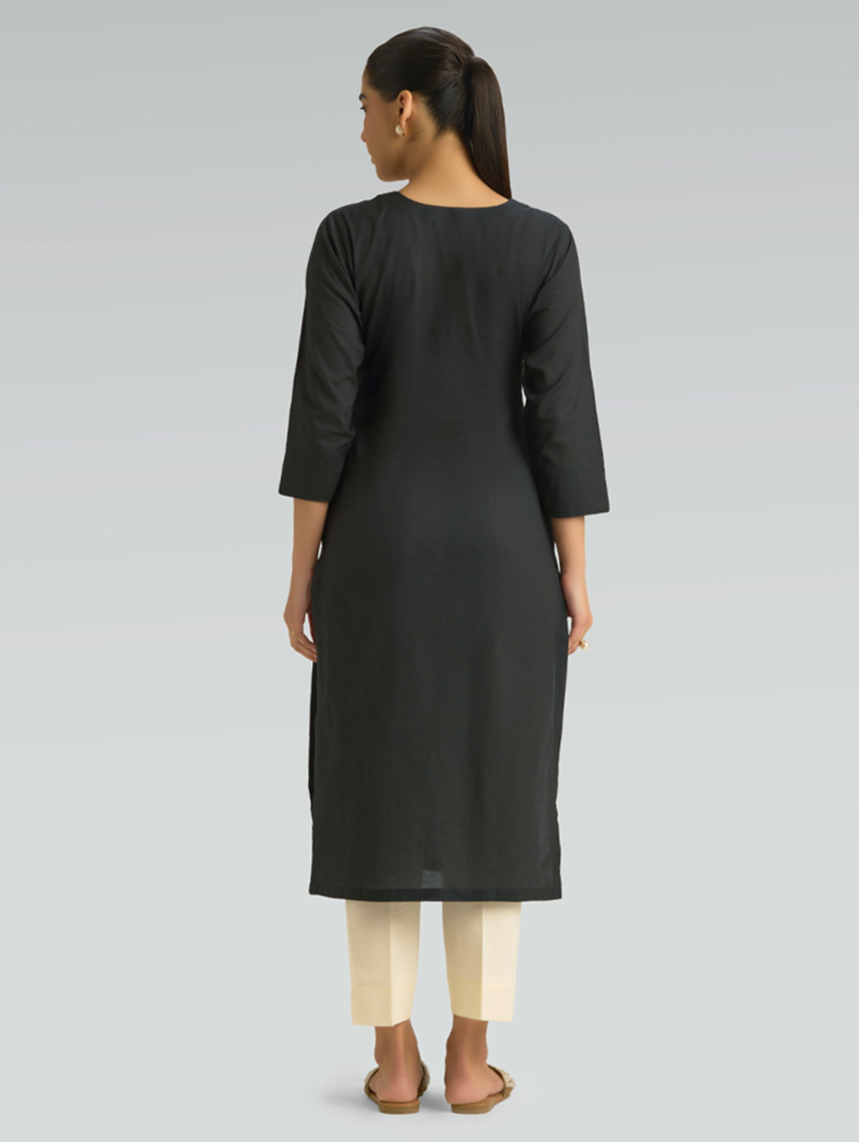 Woman wearing a black kurta with white pants on a light gray background