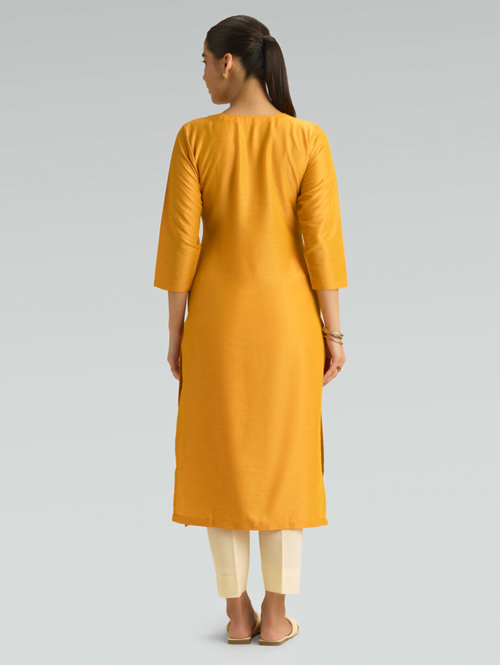 A woman wearing a Moon yellow kurta with plain backside fabric, white pants on a grey background
