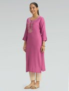 Woman wearing a pink kurta with embroidery on a gray background