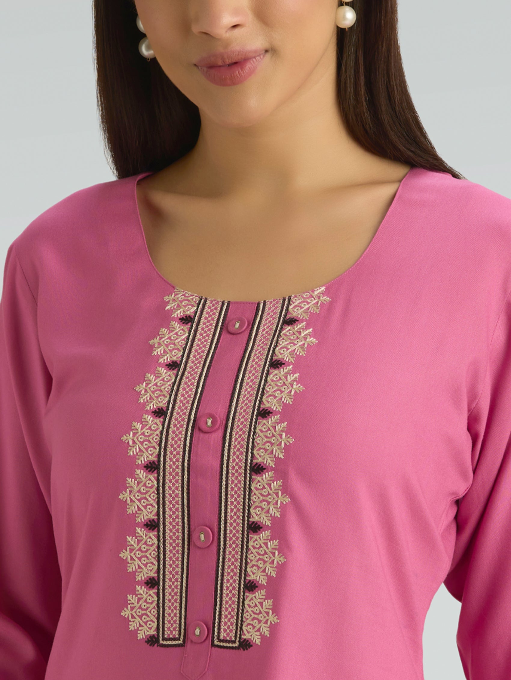 Close-up of a pink top with intricate embroidery on a grey background