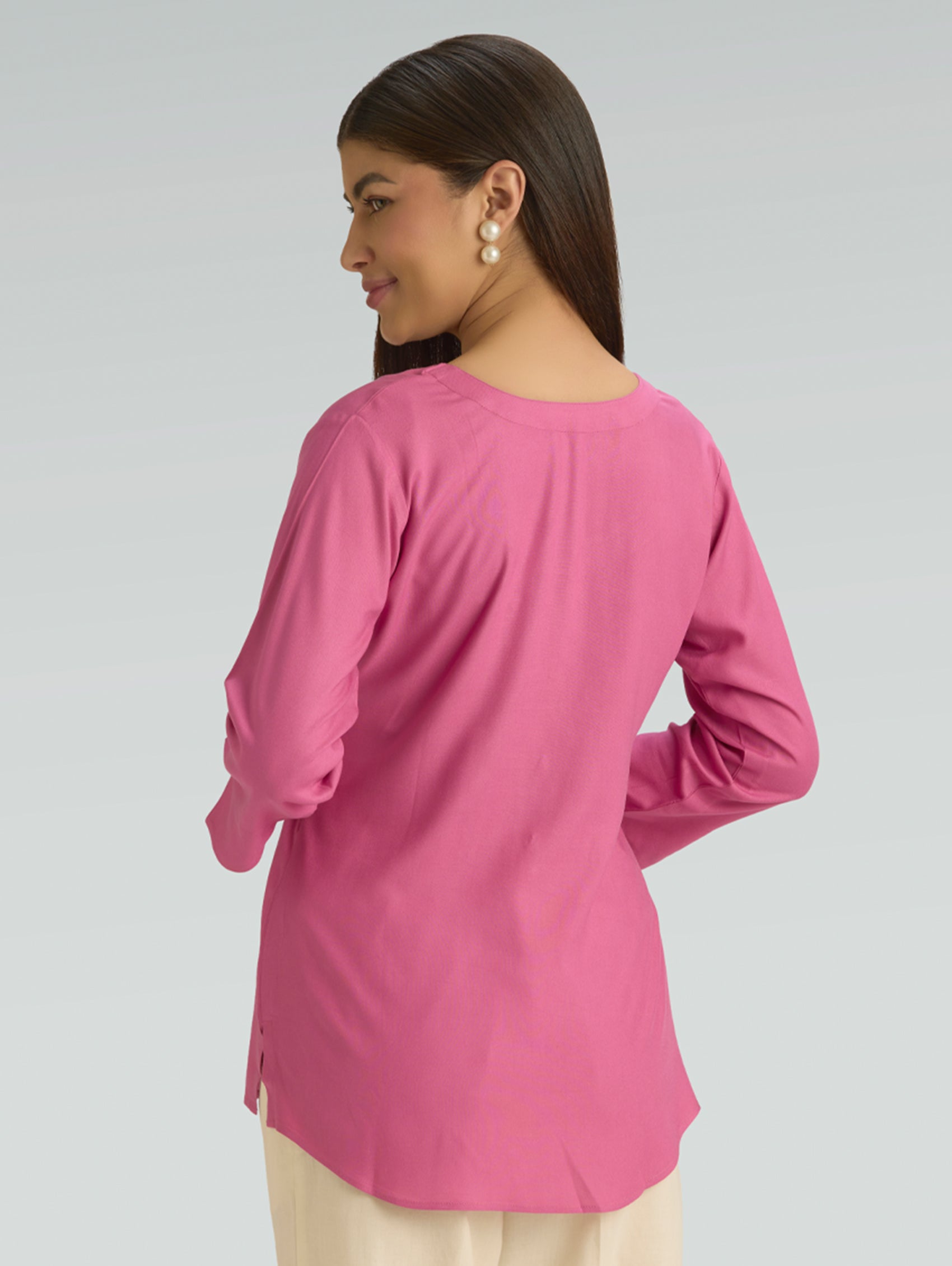 Woman wearing a pink short kurti on a gray background