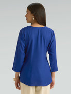 Woman wearing a blue top with a plain background