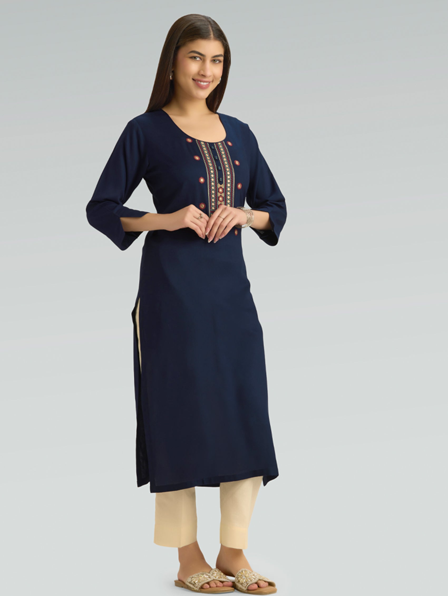 Woman wearing a navy blue kurta with beige pants on a gray background
