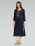 Woman wearing a navy blue kurta with embroidery on a gray background