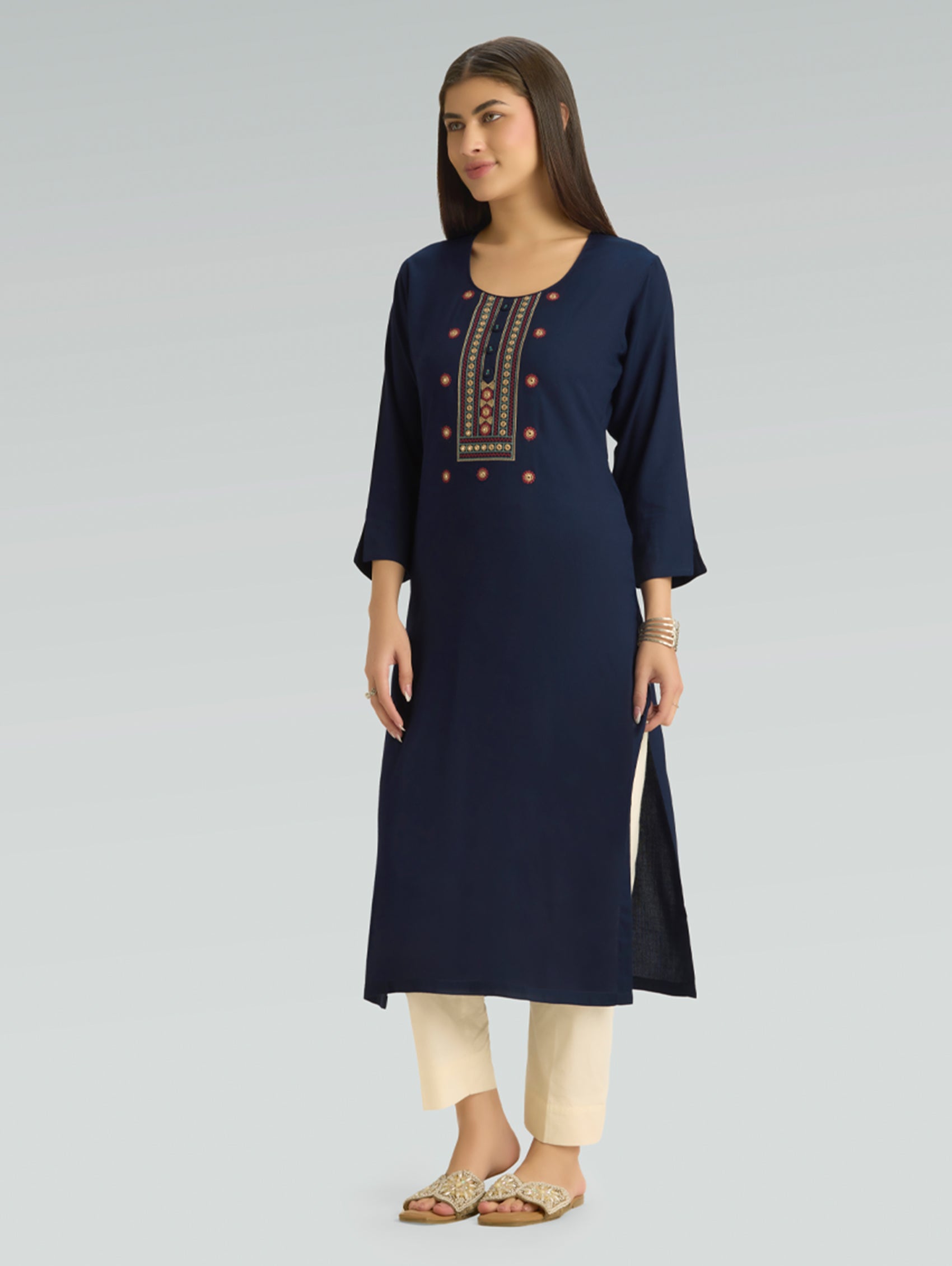 Woman wearing a navy blue kurta with embroidery on a gray background