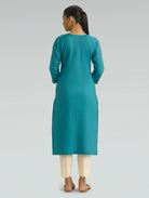 Woman wearing an Iris Blue kurta with beige pants on a grey background