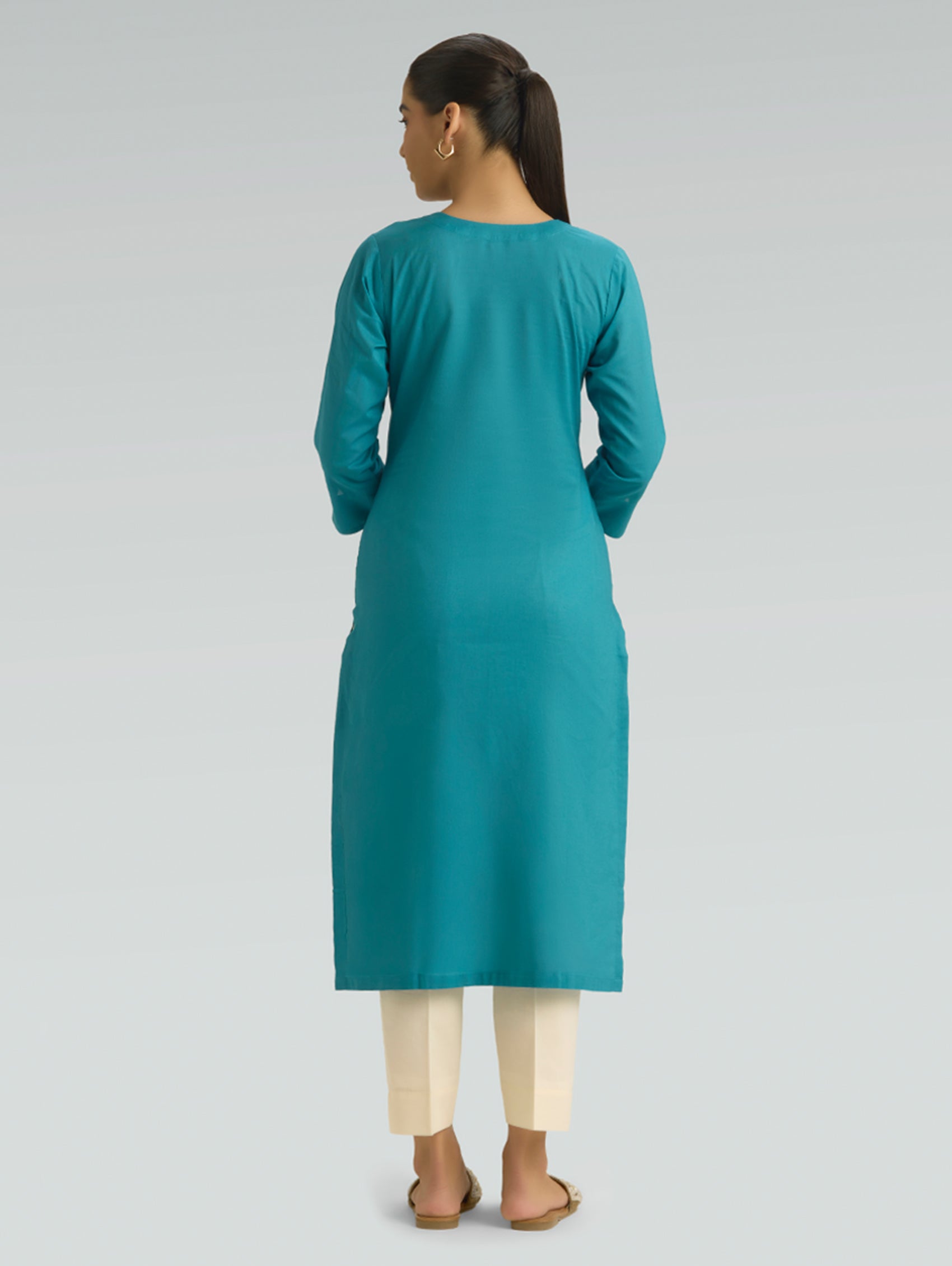 Woman wearing an Iris Blue kurta with beige pants on a grey background