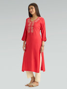 Woman wearing a red kurta with white embroidery on a gray background