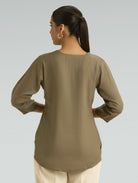 Woman wearing a green blouse against a gray background