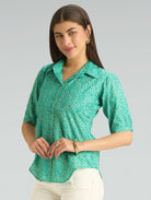 Woman wearing a green patterned shirt against a gray background