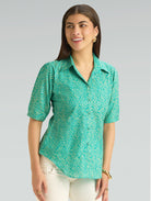 Woman wearing a green patterned shirt against a gray background
