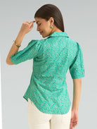 Woman wearing a green patterned blouse against a gray background