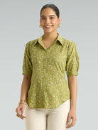Woman wearing a green patterned shirt against a gray background