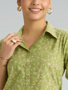 Woman wearing a green floral blouse with a plain background