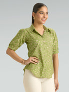 Woman wearing a green patterned shirt against a gray background