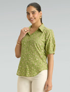 Woman wearing a green floral shirt against a gray background