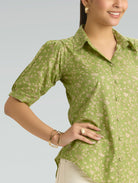Woman wearing a green floral blouse against a gray background