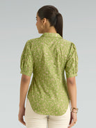 Woman wearing a green floral blouse against a light gray background