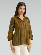 Woman wearing a green and brown striped shirt against a gray background