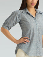 Woman wearing a gray and white patterned shirt against a plain background