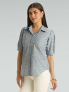 Woman wearing a patterned shirt with a plain background