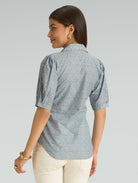 Woman wearing a patterned shirt with short sleeves on a plain background