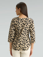 Woman wearing a patterned blouse with long sleeves on a plain background