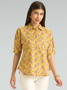 Woman wearing a yellow and pink chevron patterned blouse on a gray background