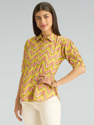 Woman wearing a yellow and pink chevron patterned shirt on a gray background