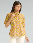 Woman wearing a yellow and pink patterned blouse against a gray background