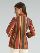 Woman wearing a colorful striped jacket on a plain background