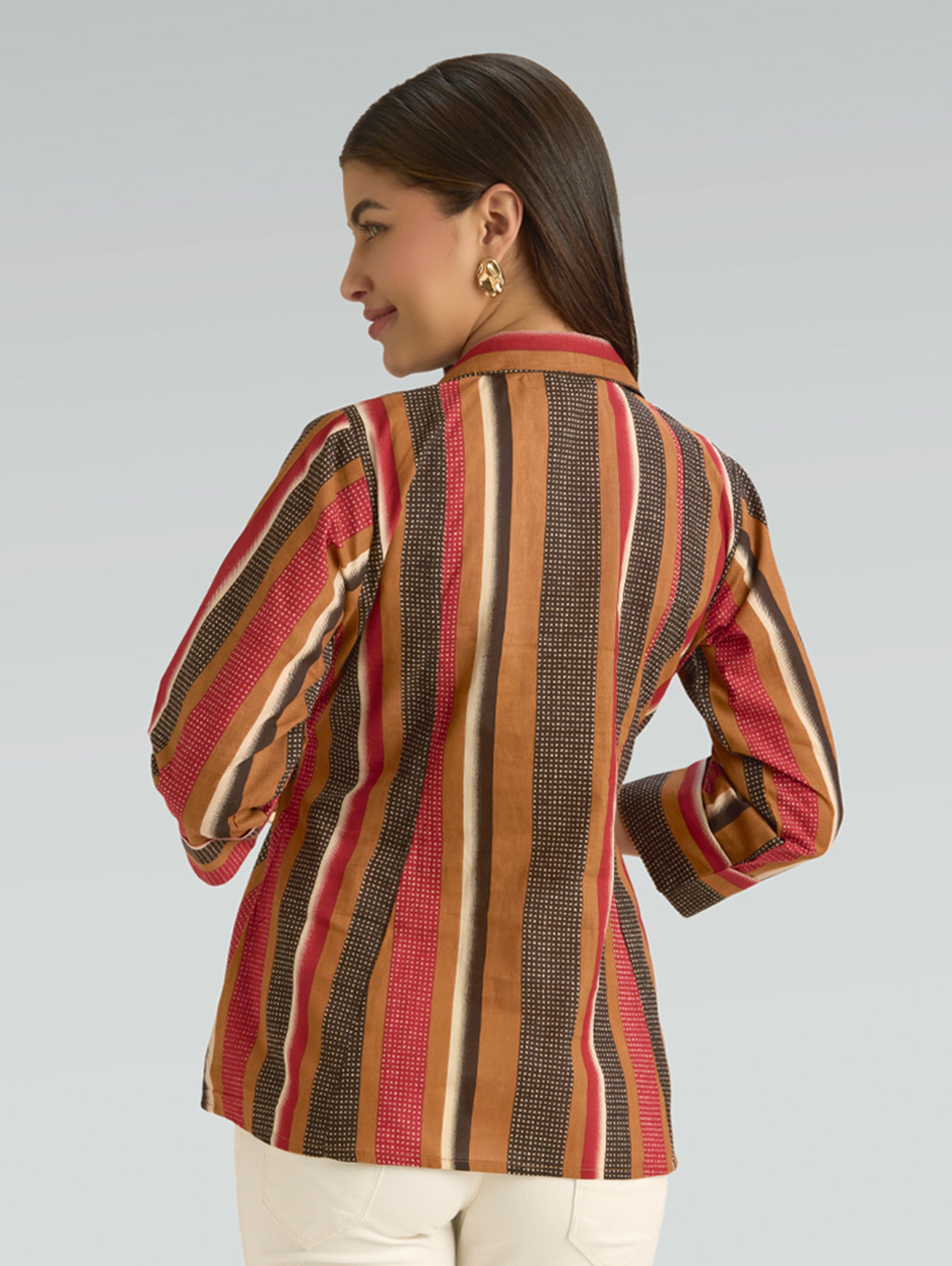 Woman wearing a colorful striped jacket on a plain background