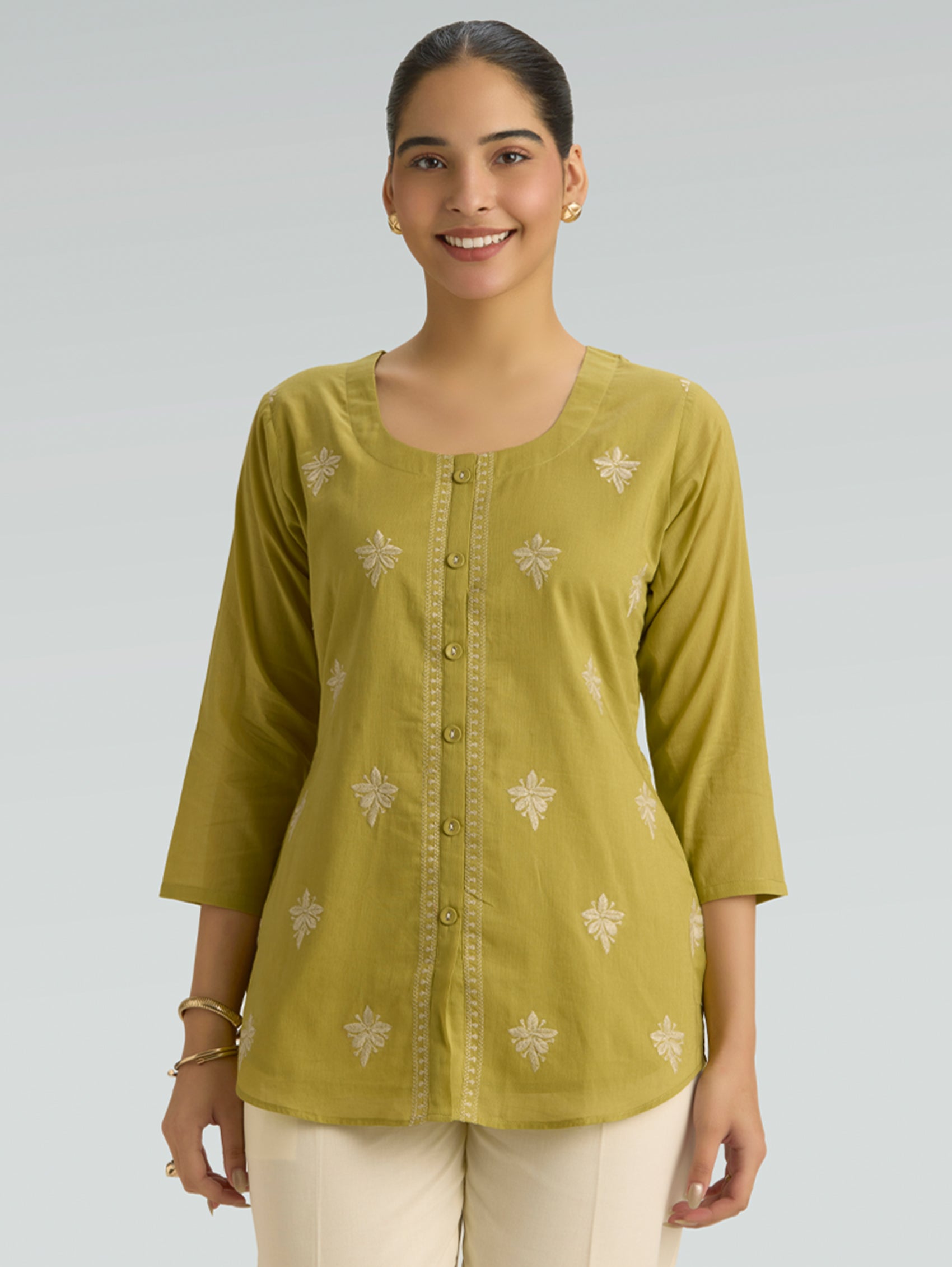 Woman wearing a green top with a plain background