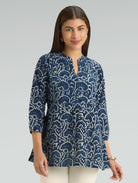 Woman wearing a blue patterned blouse against a gray background