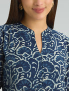 Woman wearing a blue and white patterned blouse against a neutral background