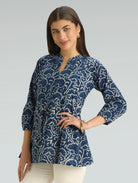 Woman wearing a blue patterned top against a gray background