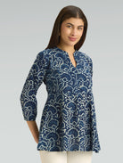 Woman wearing a blue patterned shirt against a gray background