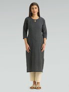 Woman wearing a dark grey patterned kurta with  side slit and beige pants on a light grey background
